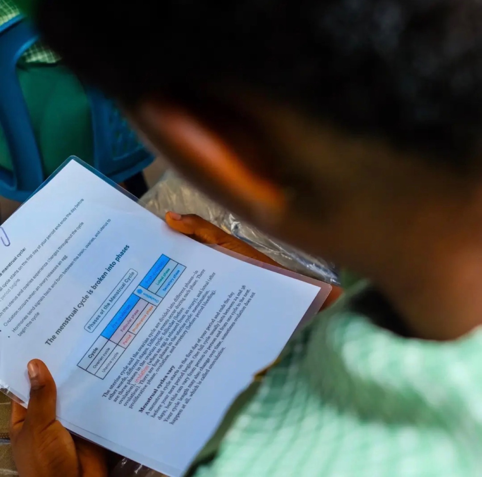 A student reading her take-home health and hygiene guide at the Sagamu outreach, 2026